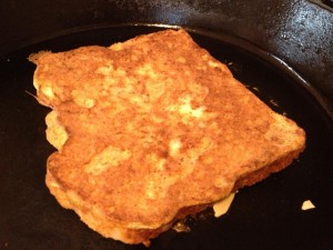 french toast cooking in pan with almonds on top